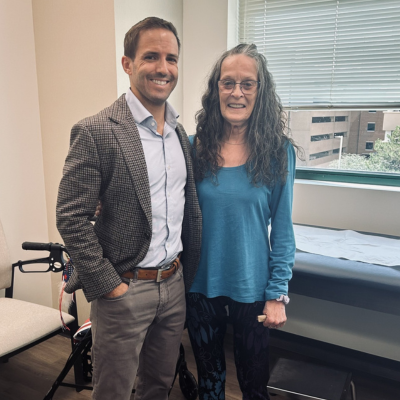 Dr. Baran and Leatha stand next to each other and celebrate the success of her surgery.