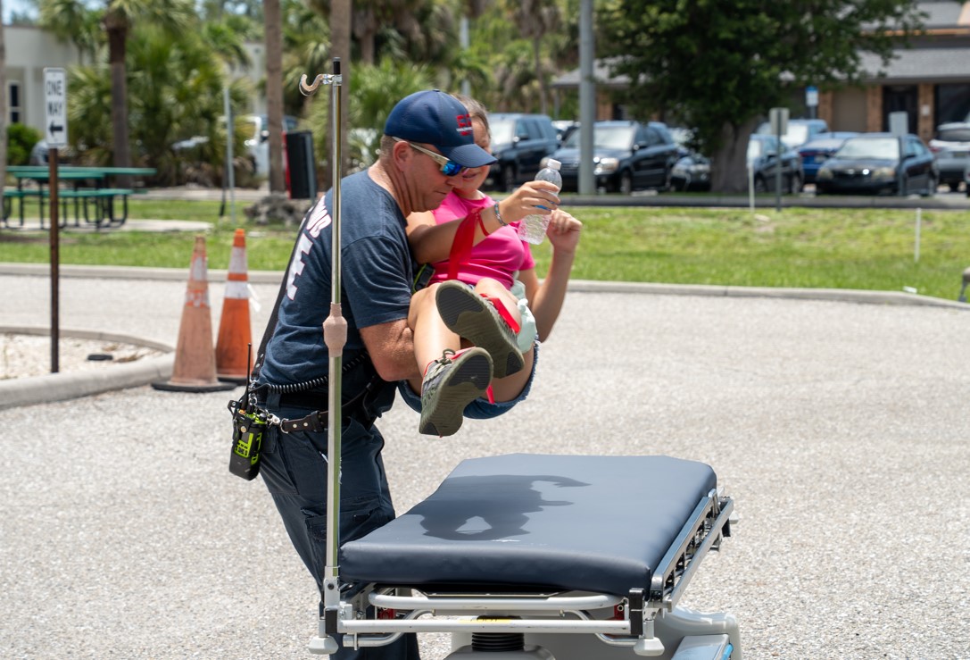 Englewood firefighter carrying a young mock 'victim' to safety during a simulated school bus crash at HCA Florida Englewood hospital