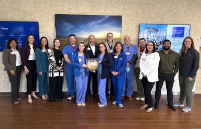 Hospital staff pose for group photo with accreditation seal poster