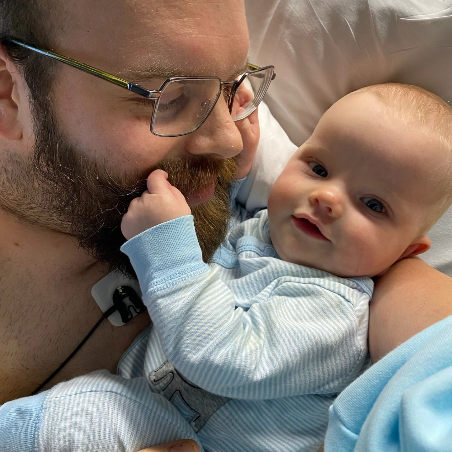 Matthew Flowers holding his baby while recovering in a hospital bed.