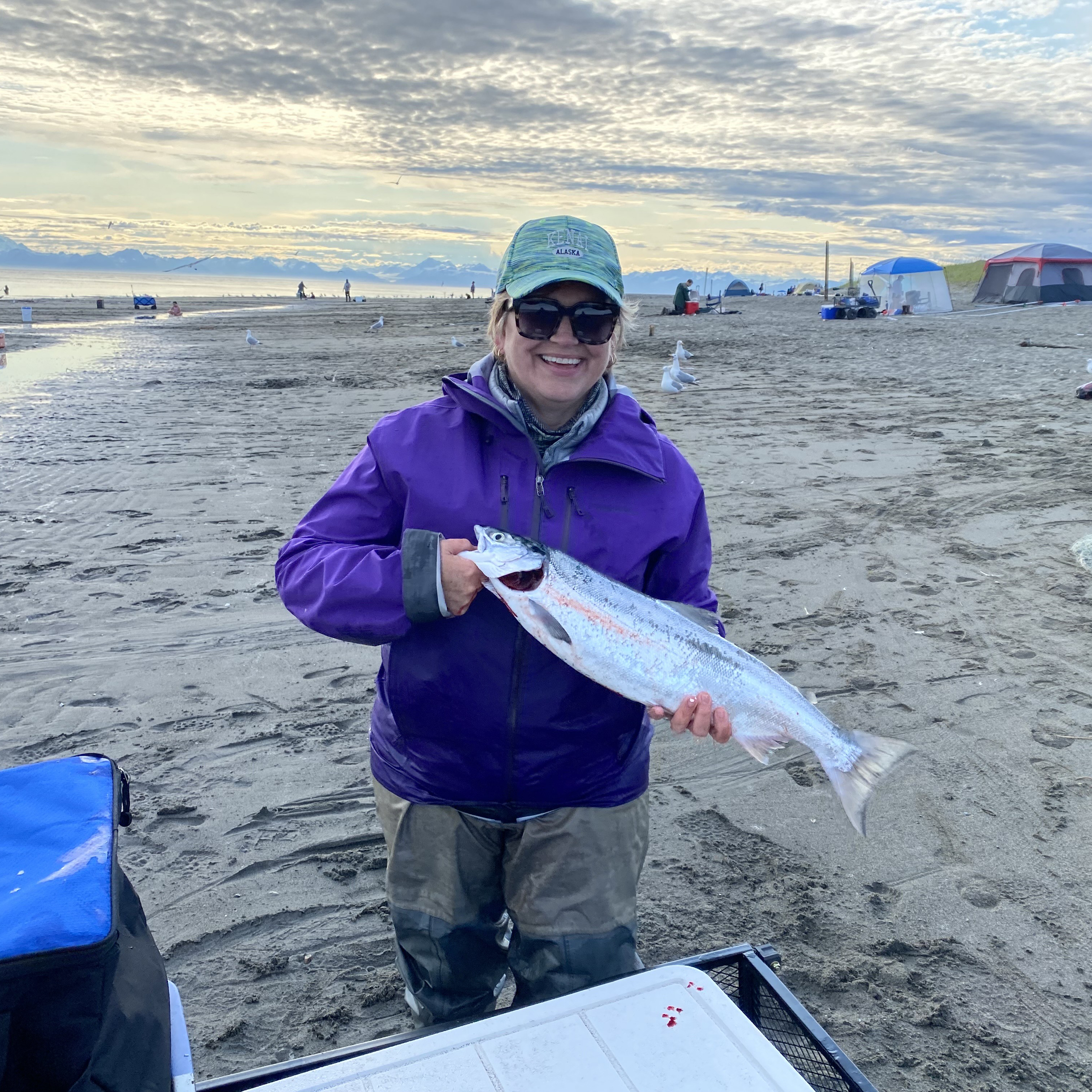 Liisa Anderson holds a fish while standing on a beach