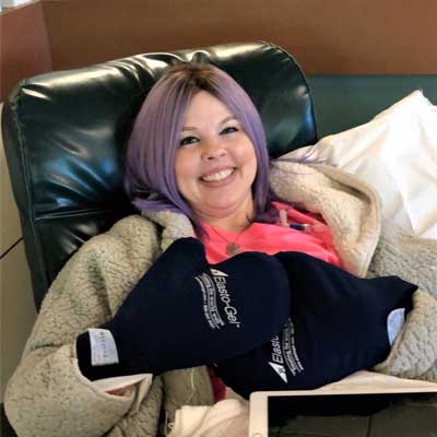 Stacy Ciaschini smiles while sitting on a hospital recliner, recovering after her surgery.