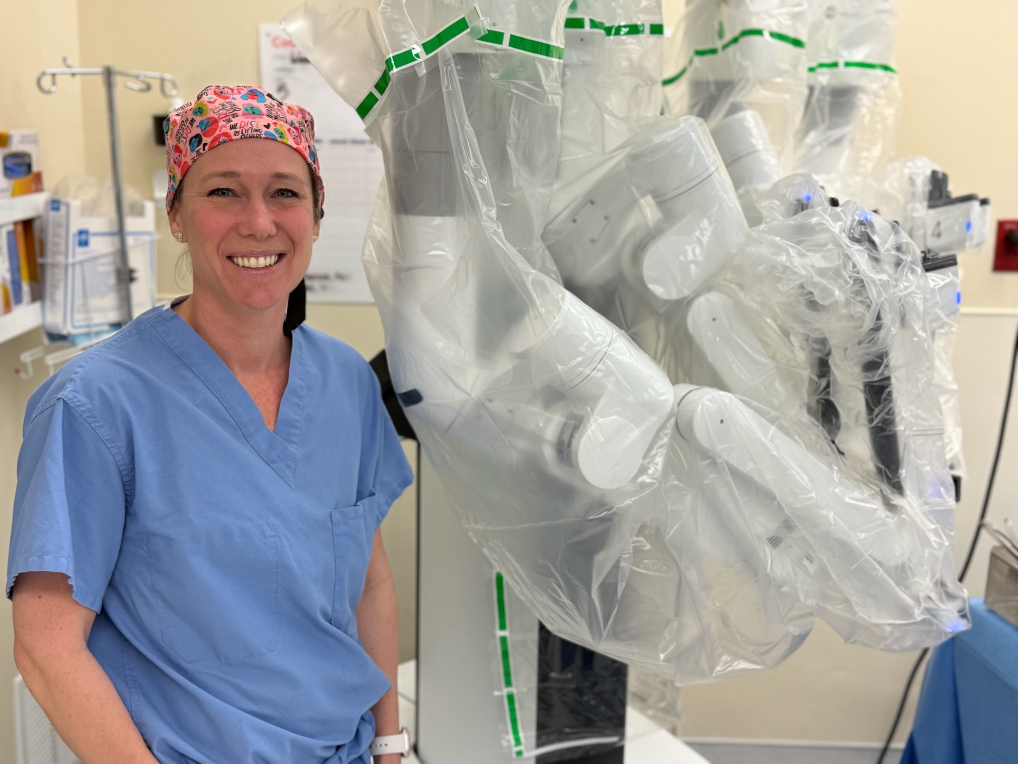 Physician stands next to new robotic surgical technology.