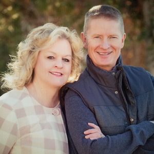 Christine Ahearn and her partner smile while standing outside on a fall day.