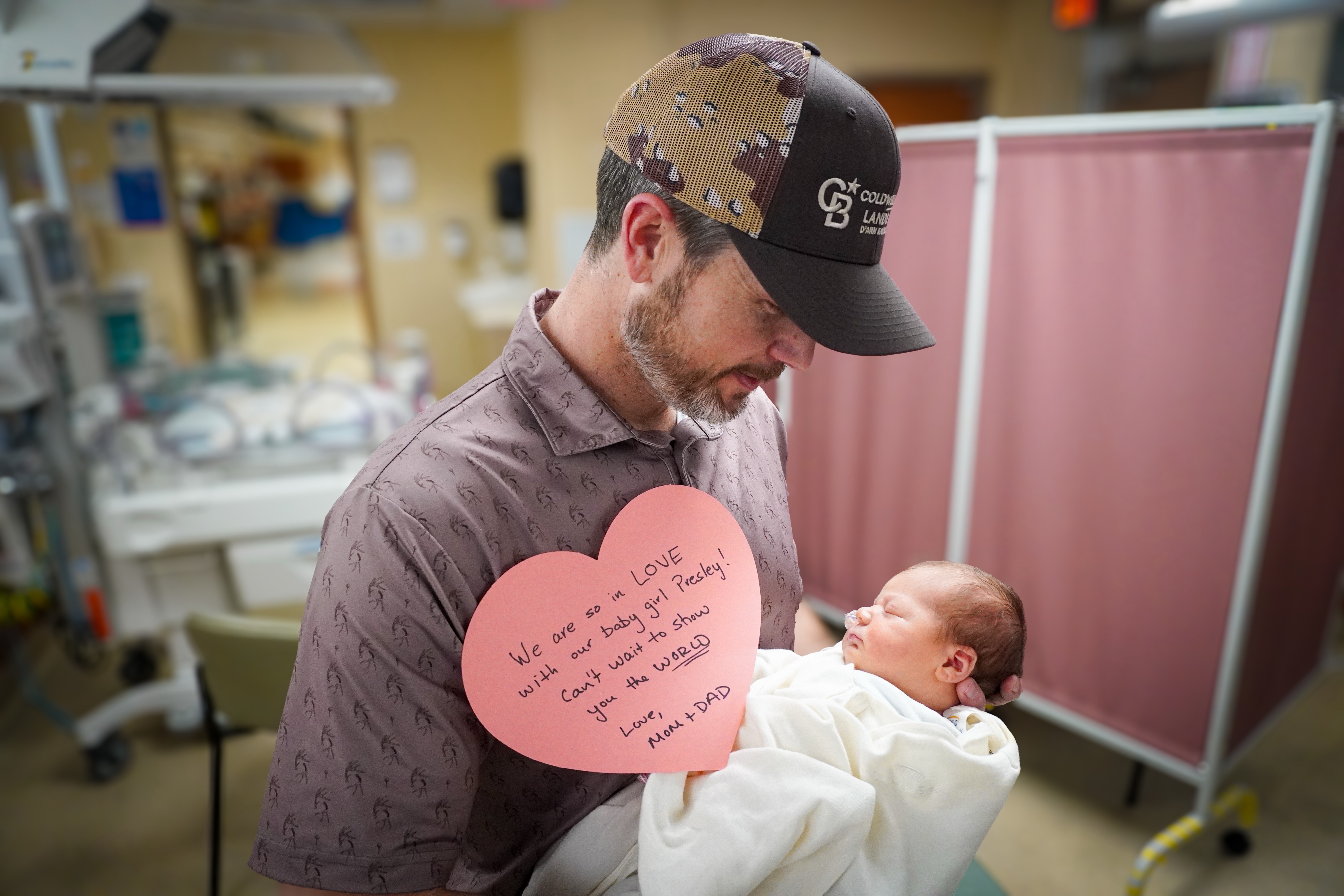 A father smiles at his baby while sharing a note of encouragement for Valentine's Day.