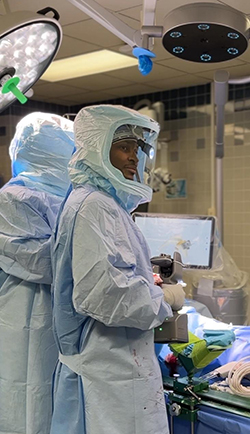 Orthopedic surgeon Dr. Timmothy Randell in full-body surgical protective clothing performs surgery at an operating table. 