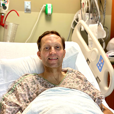 Jason Beal is positioned upright in bed, post-surgery.