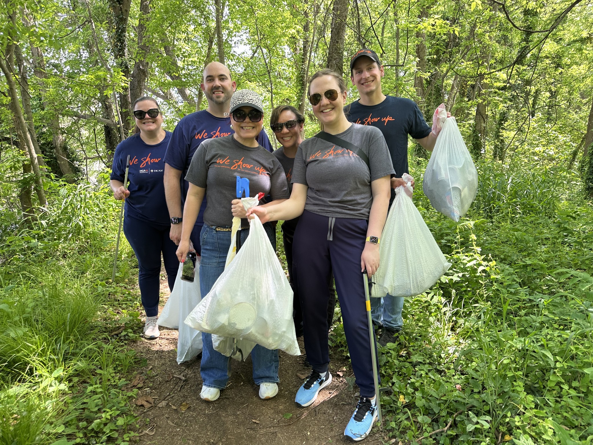HCA Virginia colleagues holding bags of trash from cleaning up a walking trail