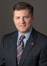 Evan Ray, wearing a suit with a multi-colored, checkered pattern tie.