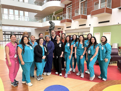 Rapides Women and Children's Hospital male and female staff dressed in hospital scrubs and medical uniforms stand as a group in lobby of hospital. 