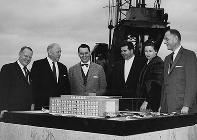 A group of people standing around a mini replica of Methodist Hospital.