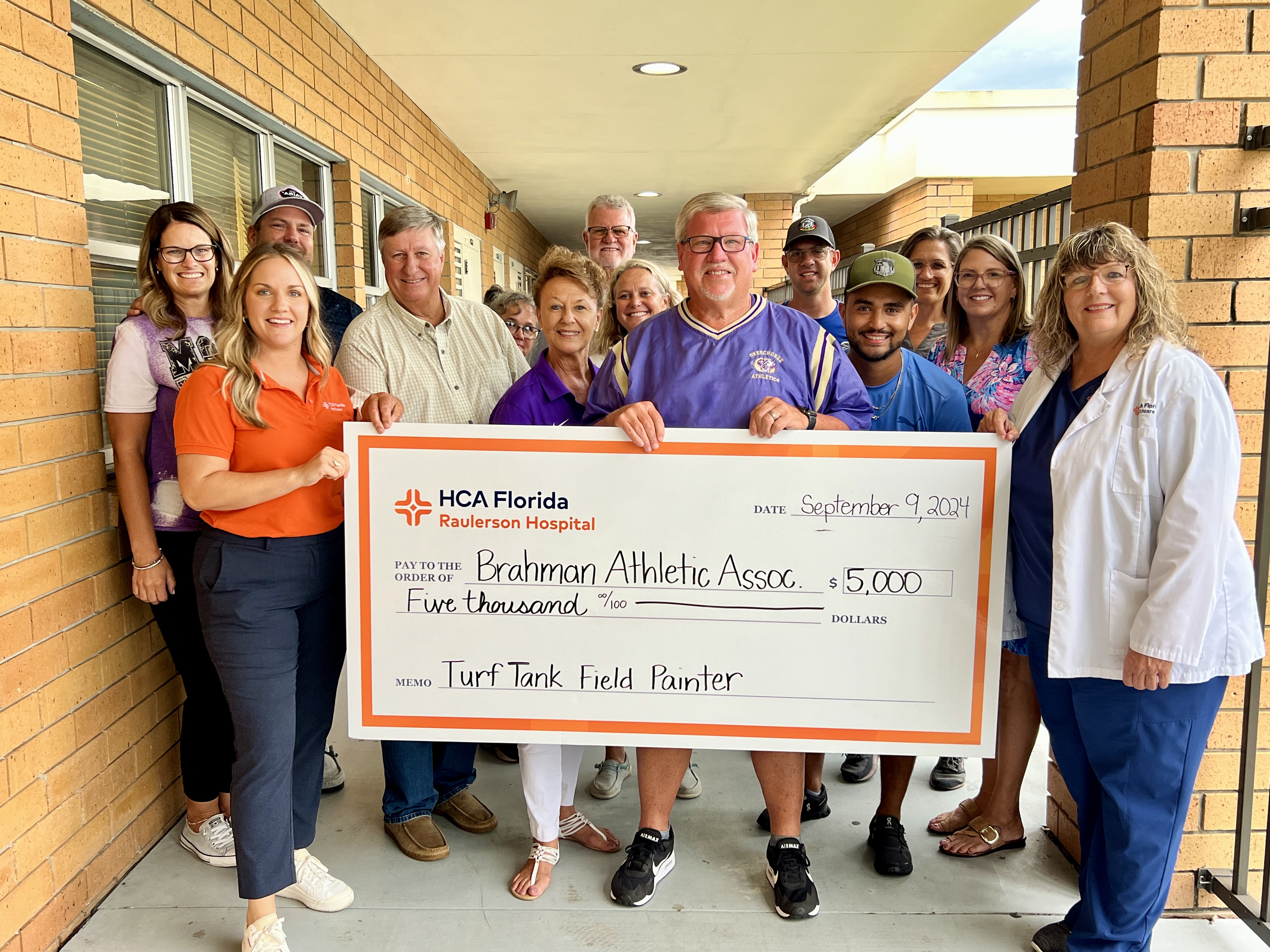 Raulerson staff holding large donation check.
