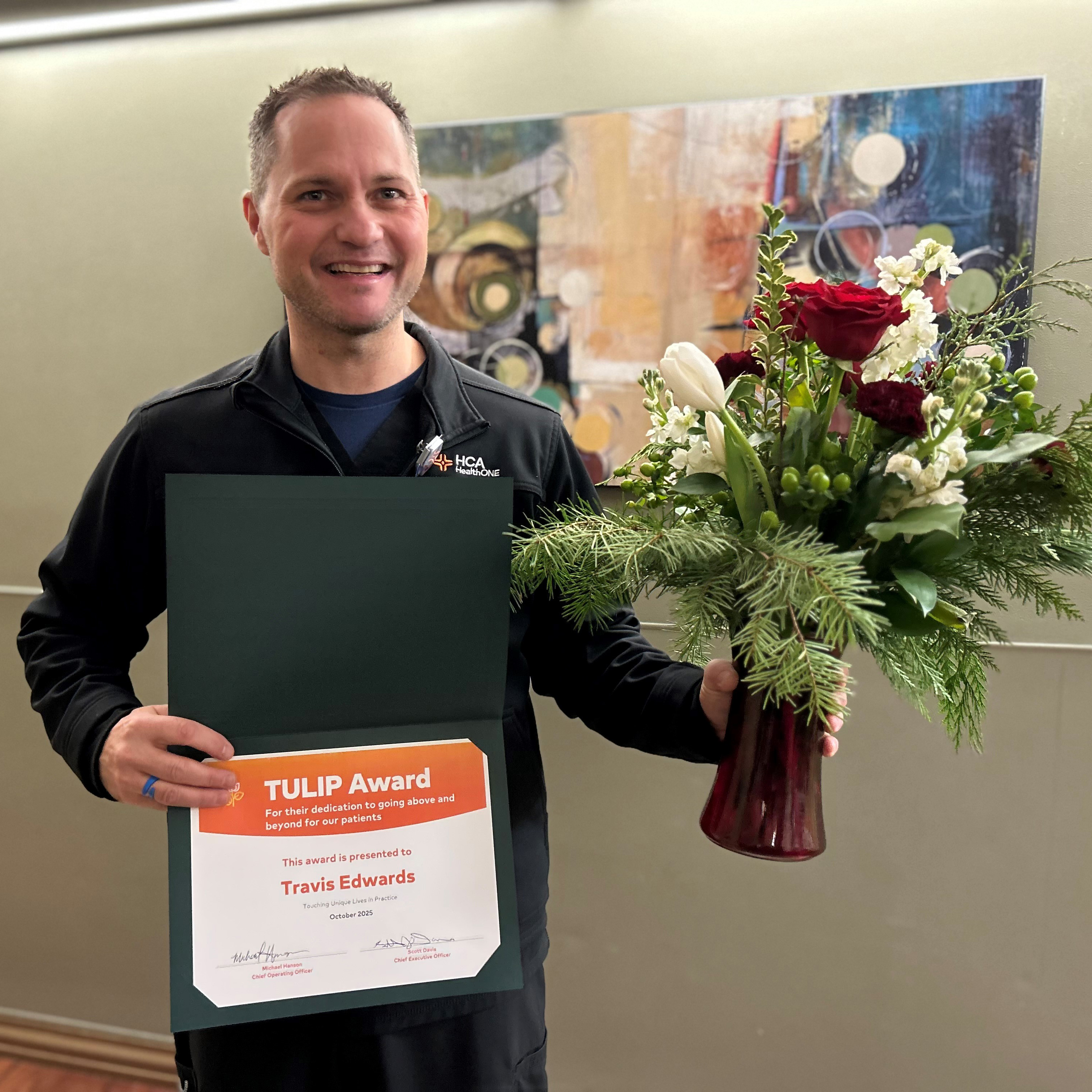 Travis Edwards with award certificate and vase of tulips.
