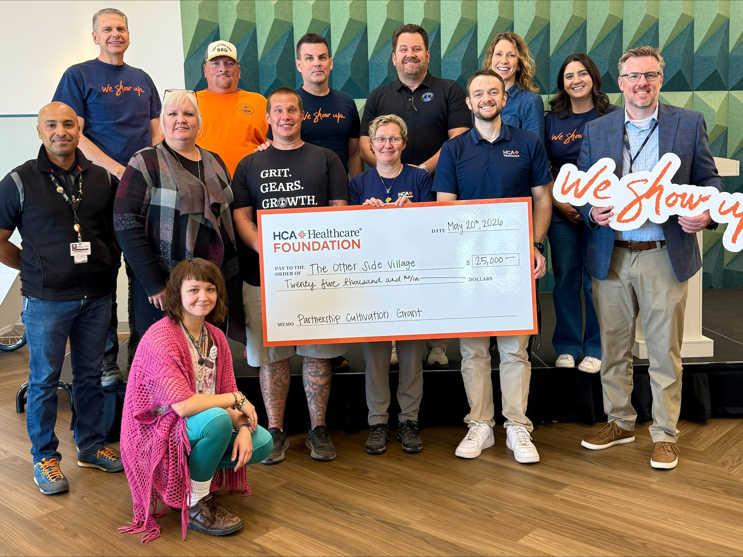 HCA team members present donation check to The Other Side Village team members.
