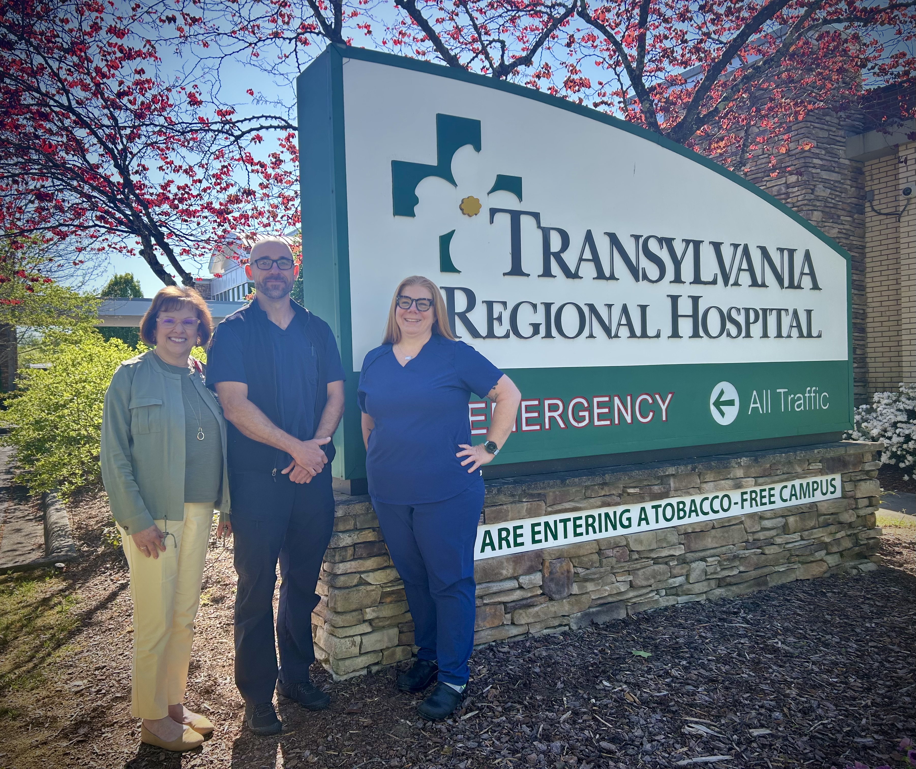 Three nurses standing outside next to the Transylvania Regional Hospital entrance.