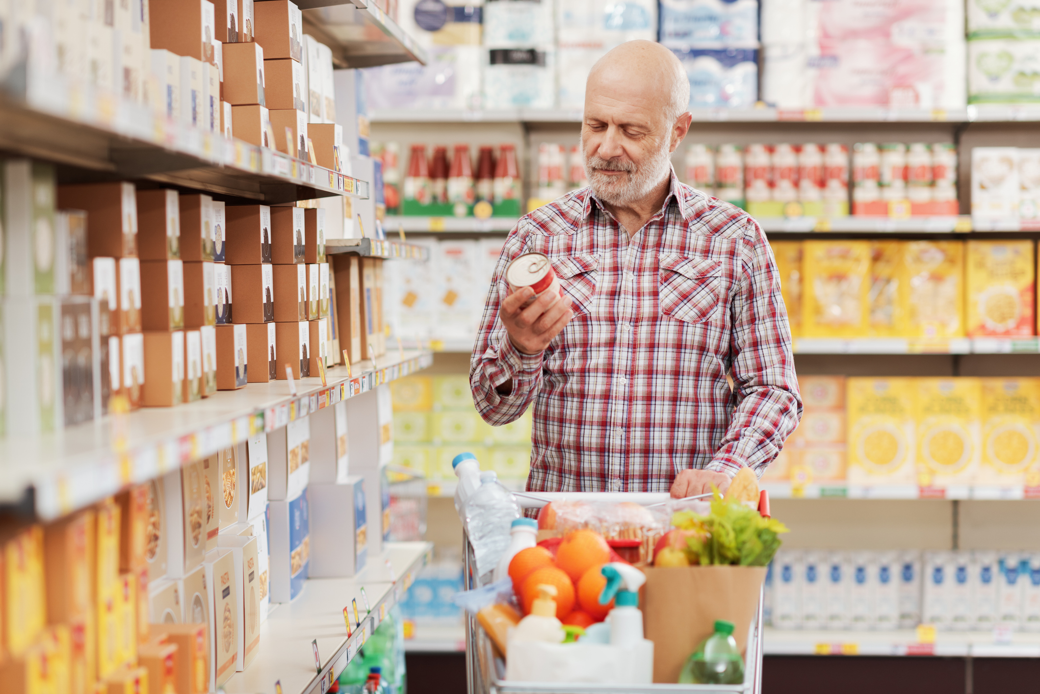 Customer holding a can and reading the product food label at the supermarket.