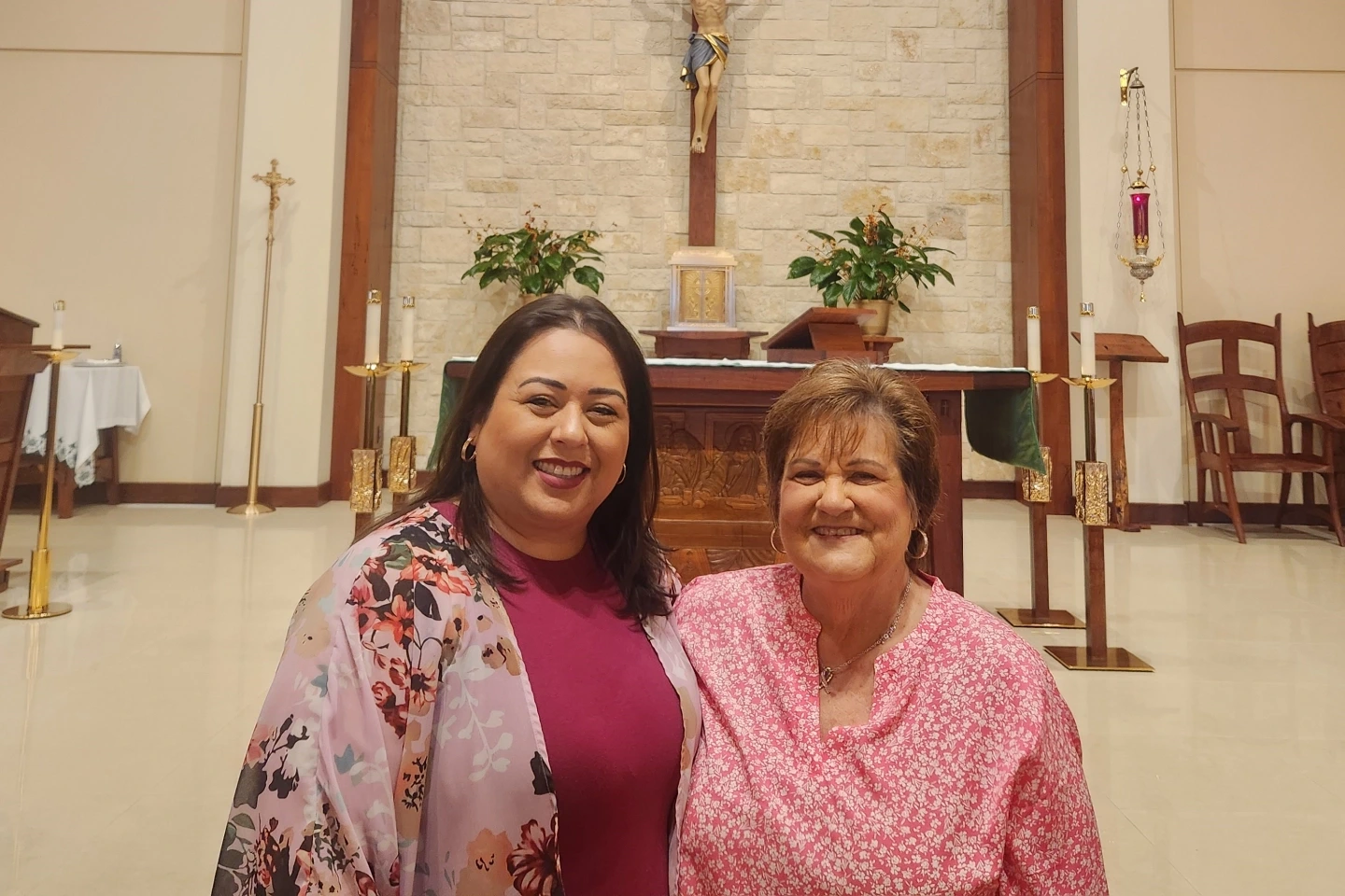 Marisol Lopez and Debbie standing in front of a cross in St. Jerome Catholic Church.