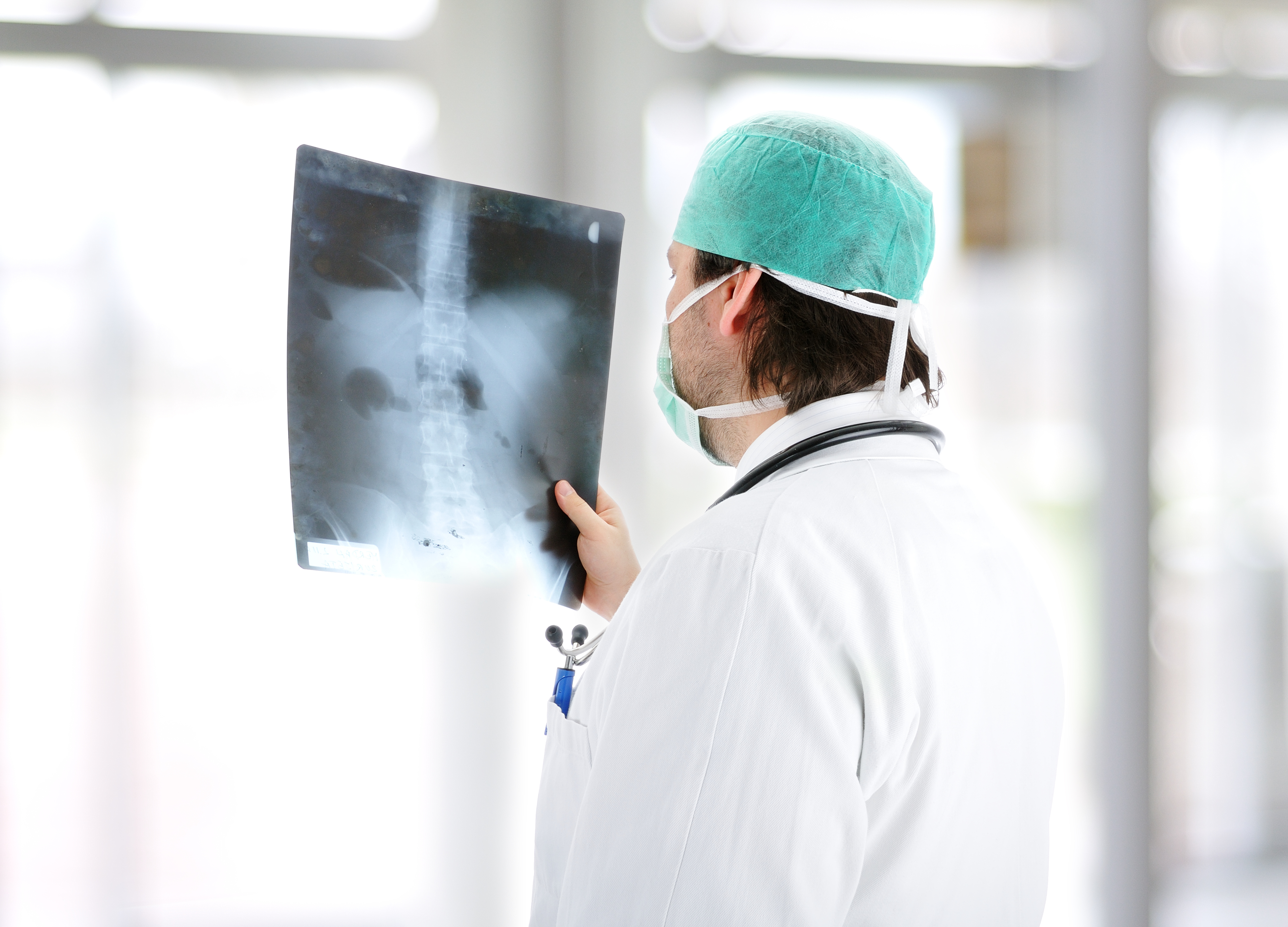 A doctor in scrubs examines an x-ray