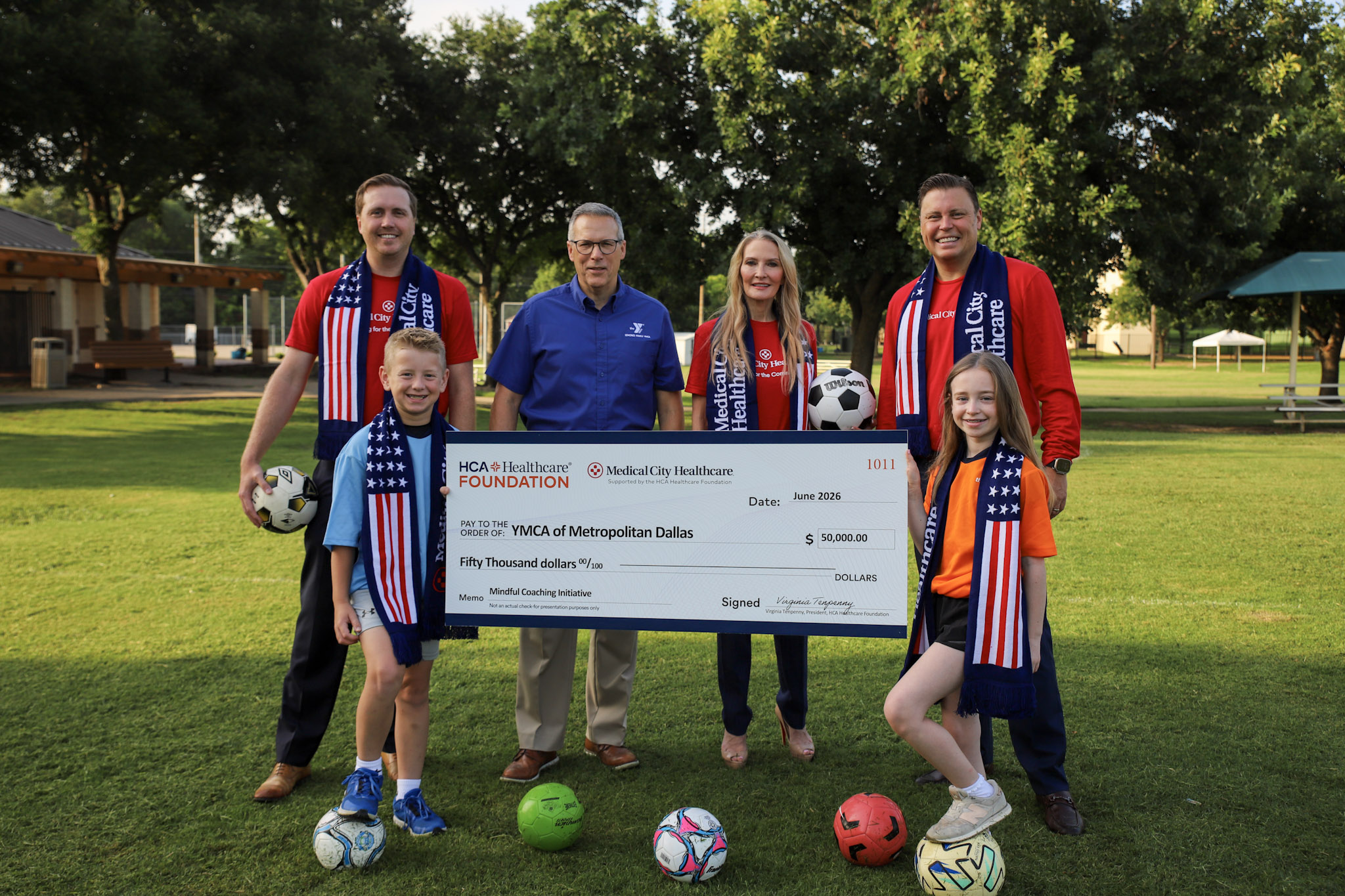 Medical City Healthcare colleagues holding a large check for the $50,000 donation to YMCA sports programs.