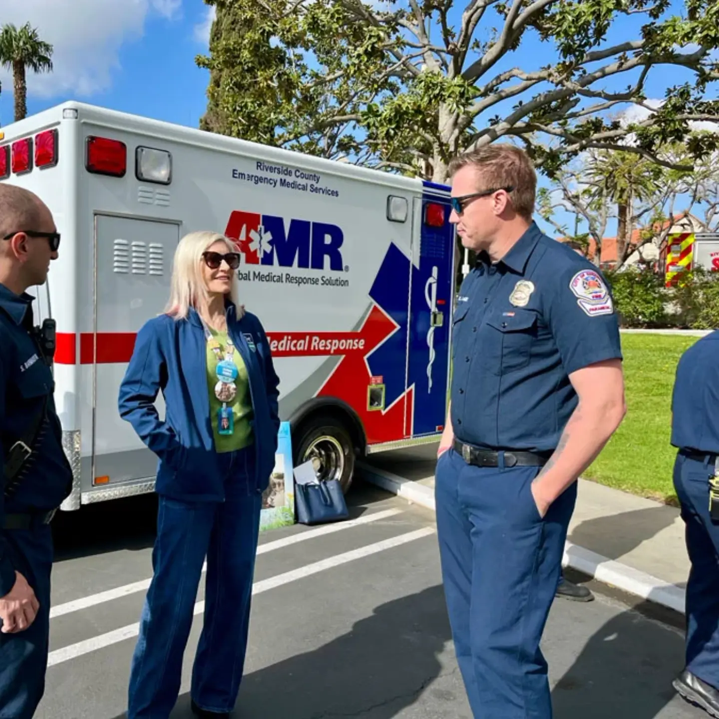 Nicole Heimerl smiles while talking with two medical professionals in front of an ambulance.