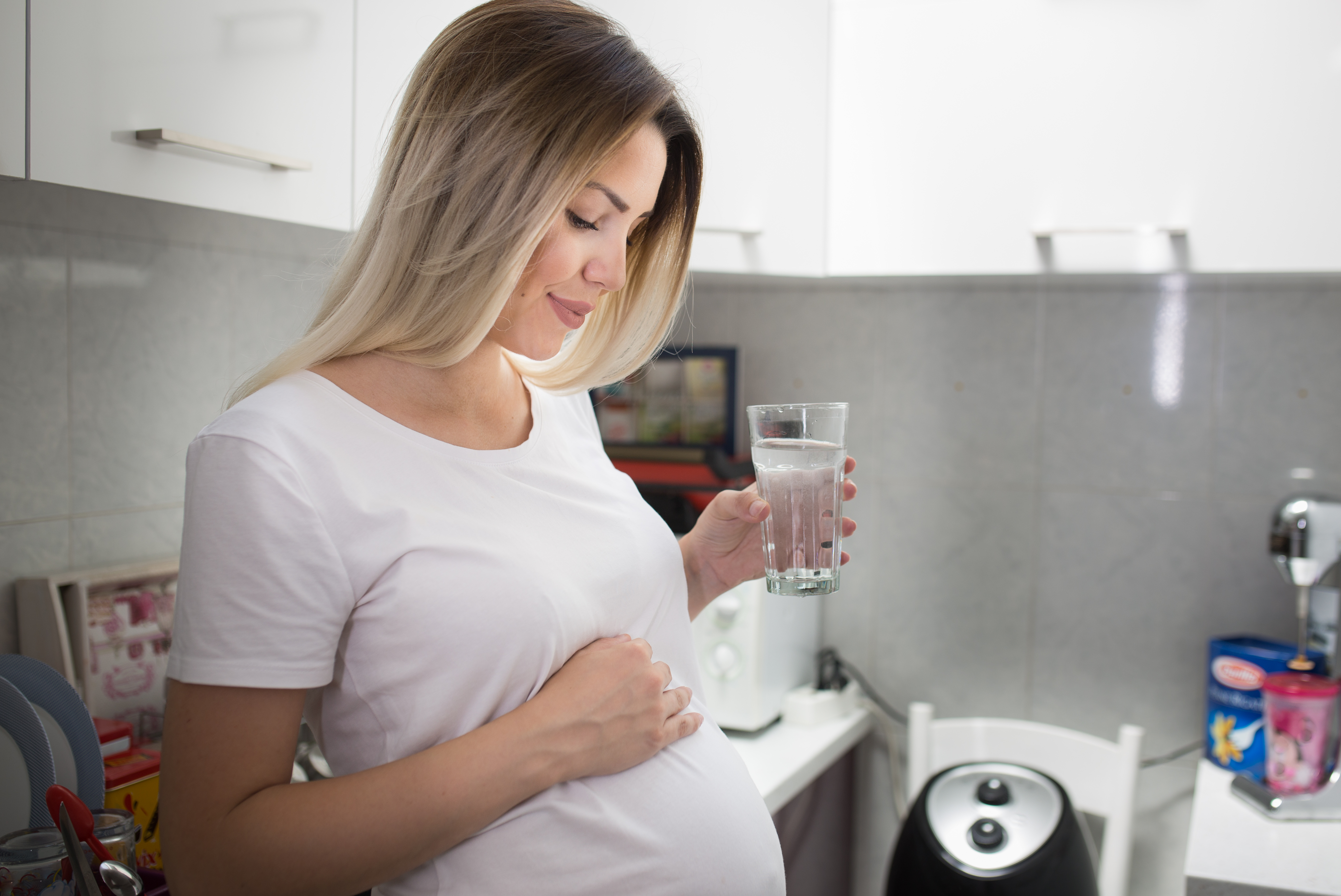 Young pregnant woman drinking water in the morning