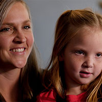 Courtney and her daughter, Raylan, smile while sitting together.