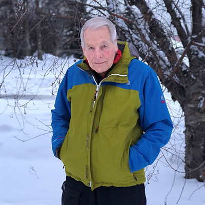 Eberhard Brunner poses outdoors, wearing a lime green and blue winter jacket.