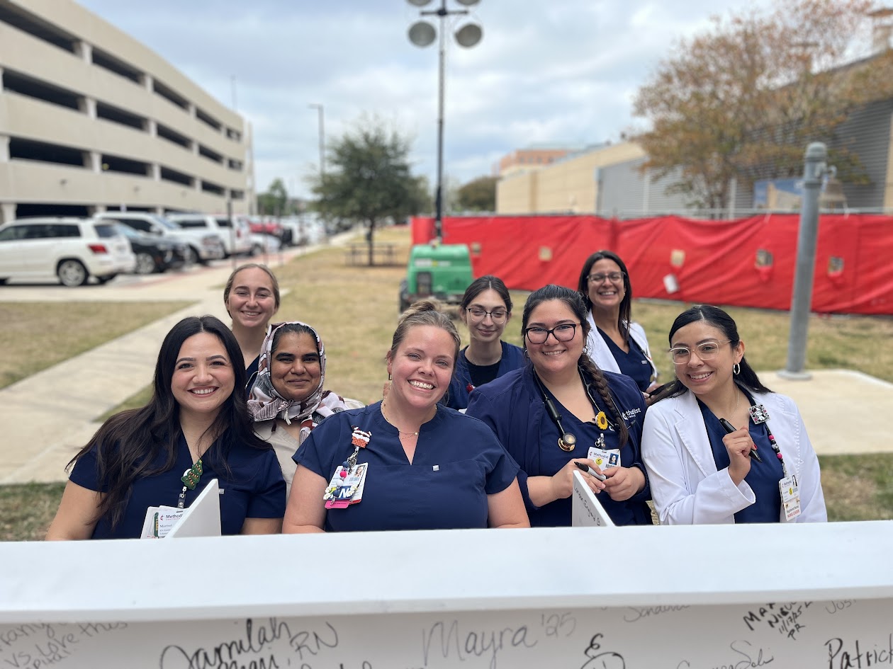 Employees by a signed white steel beam