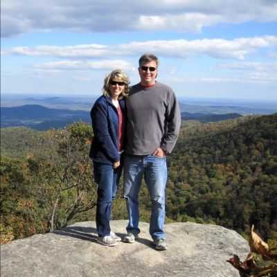 Husband and wife, Troy and Lori Barbour, pose on top of a mountain