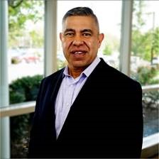 Lee Lopez, chief financial officer of Corpus Christi Medical Center, smiles while wearing a black suit jacket.