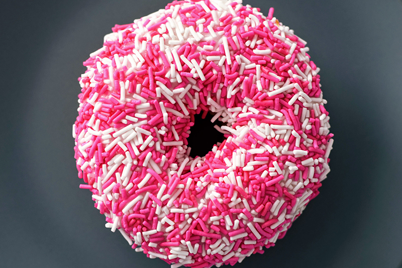 Up-close view of a pink and white sprinkle donut.