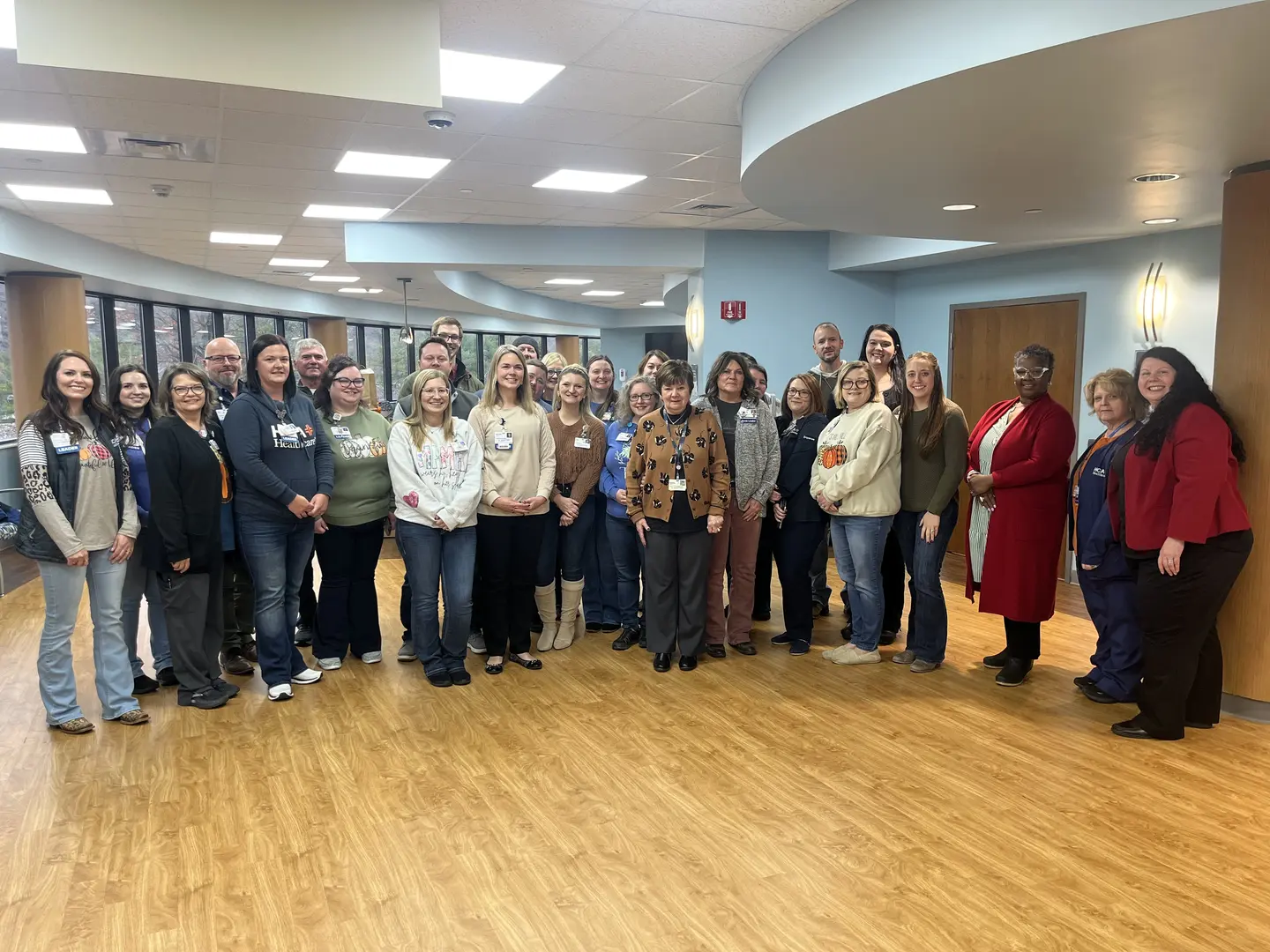 A large group of people are gathered to celebrate Brenda Woodie's 50th work anniversary.