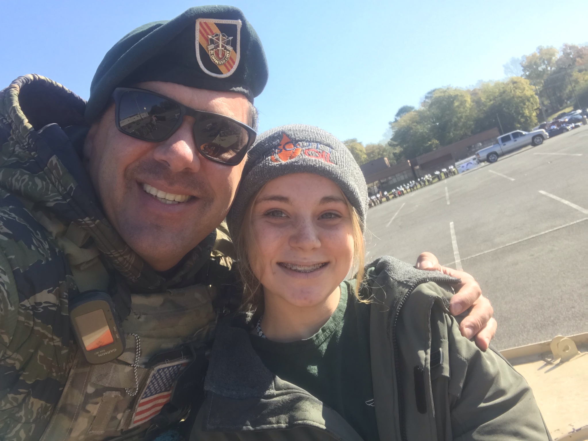 Ed Prescott, wearing his Green Beret uniform, smiles while hugging his daughter.