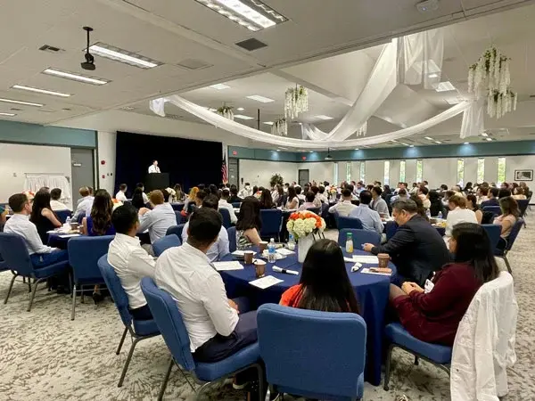 New female and male medical residents seated in conference room during orientation.