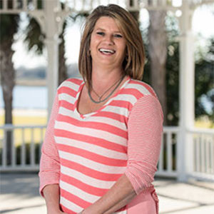 Cancer survivor Mattie Gillis smiles wearing a striped pink and white sweater.