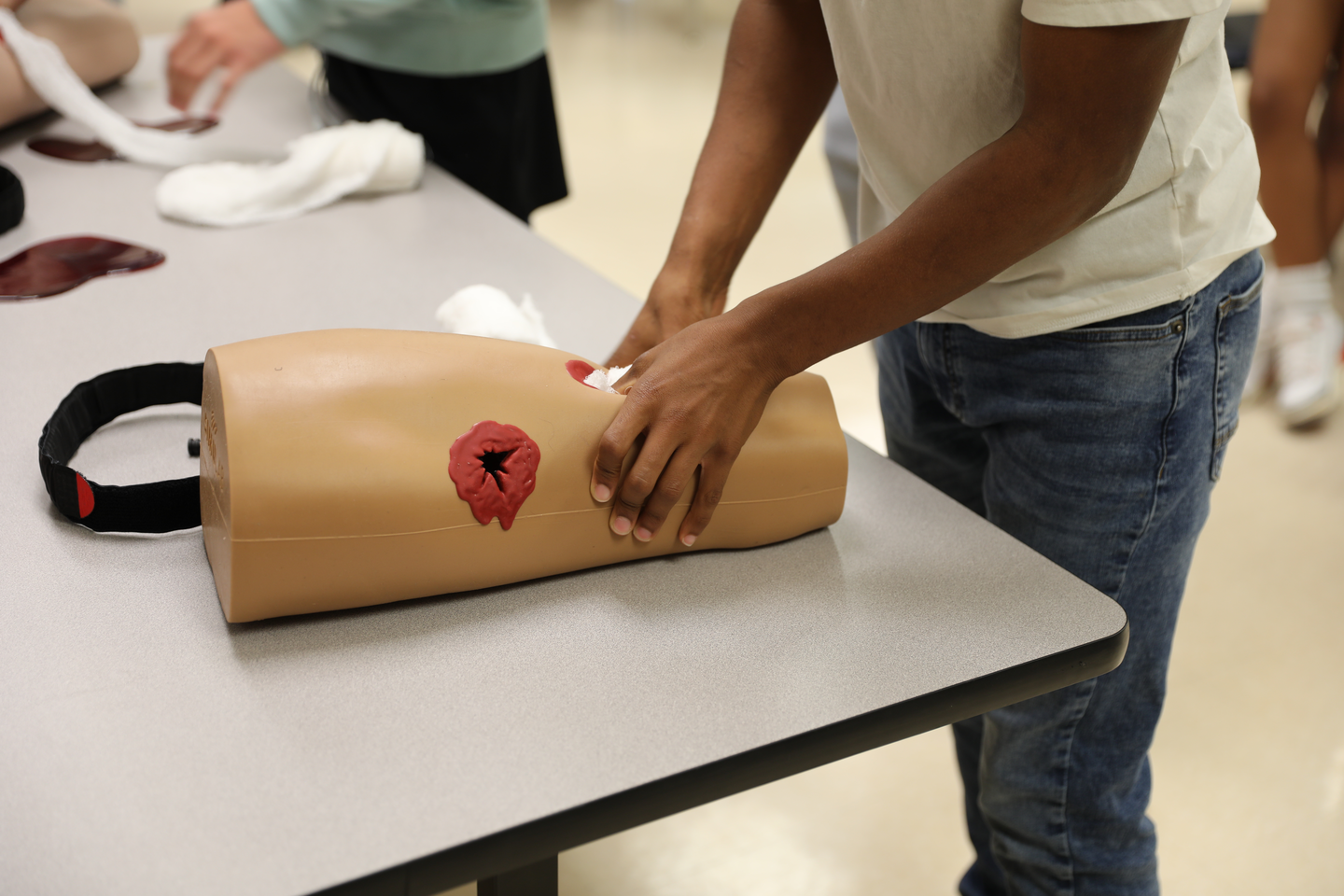 Students training with tourniquets on dummy limbs.
