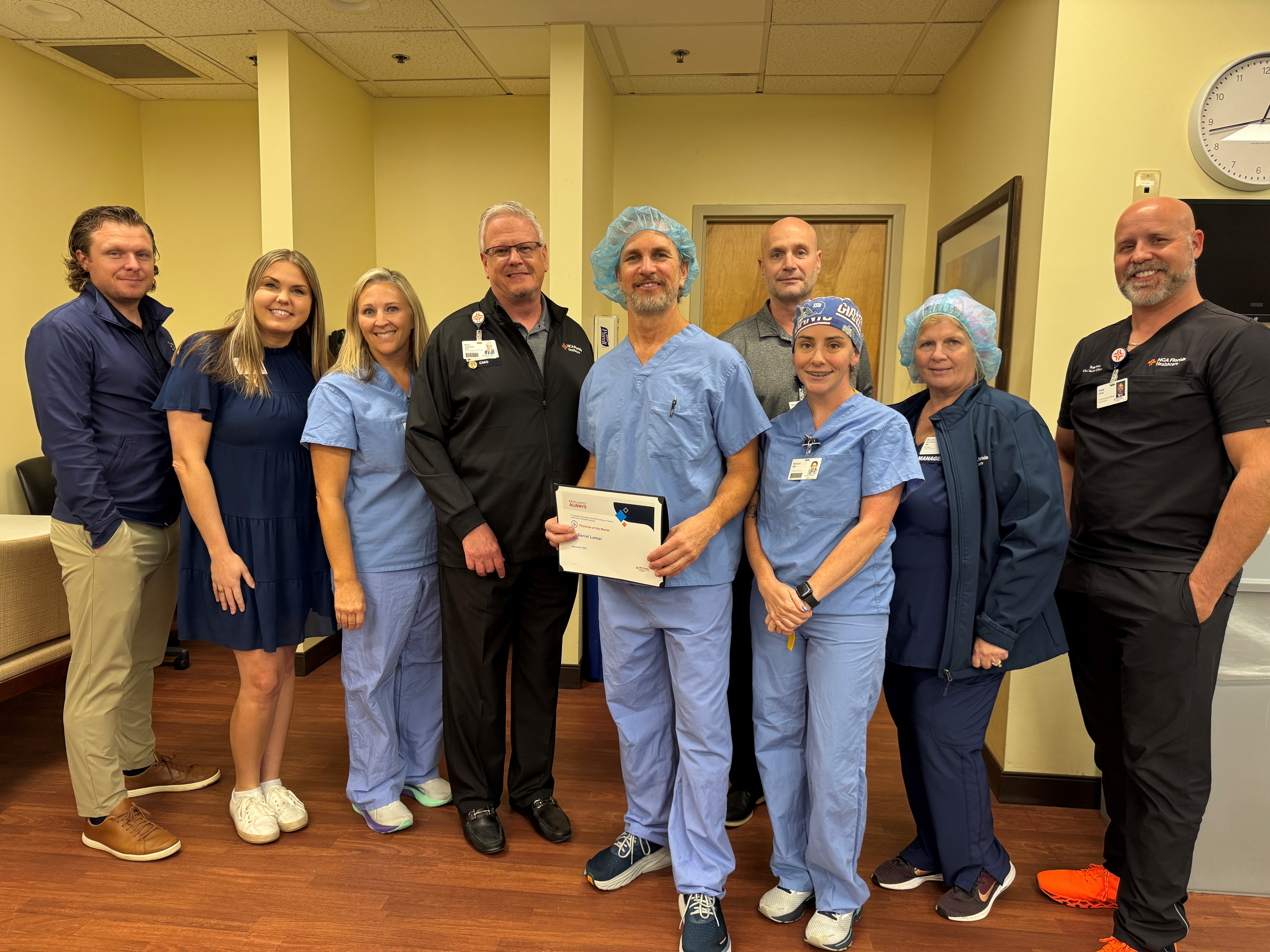 Doctor stands in middle surrounded by nurses.