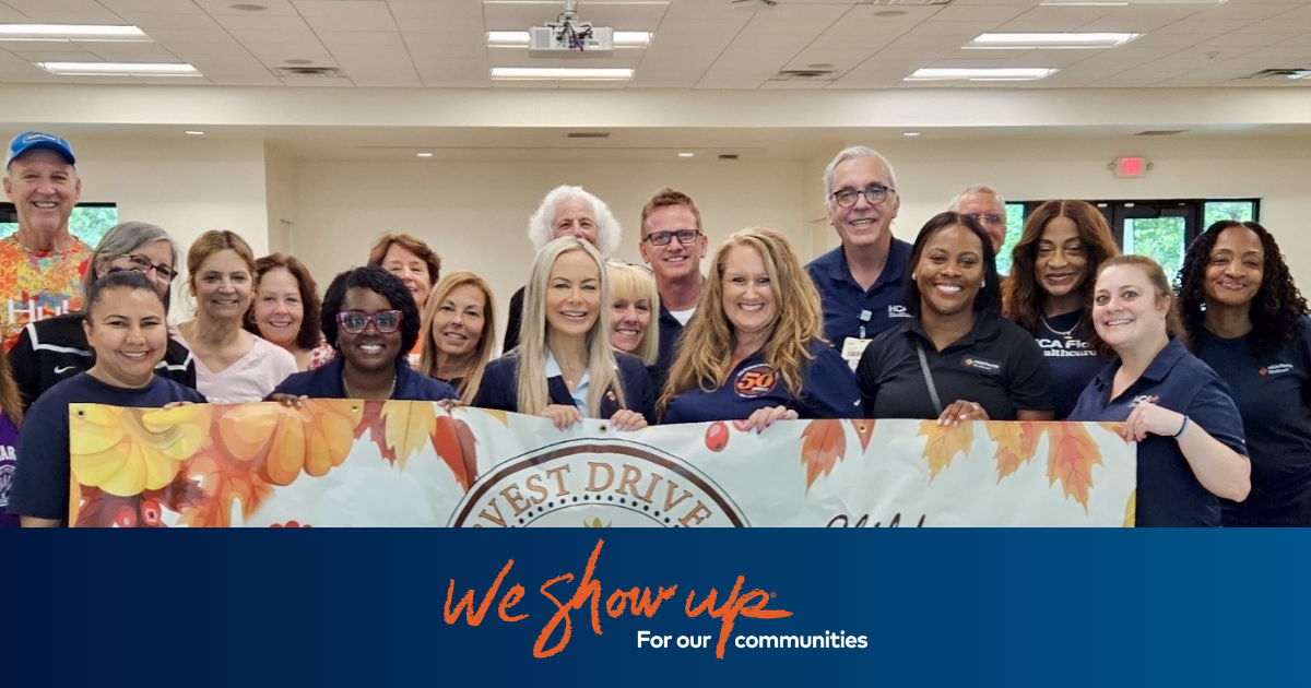 Nurses during Harvest Drive holding a We Show Up® for Our Communities banner.