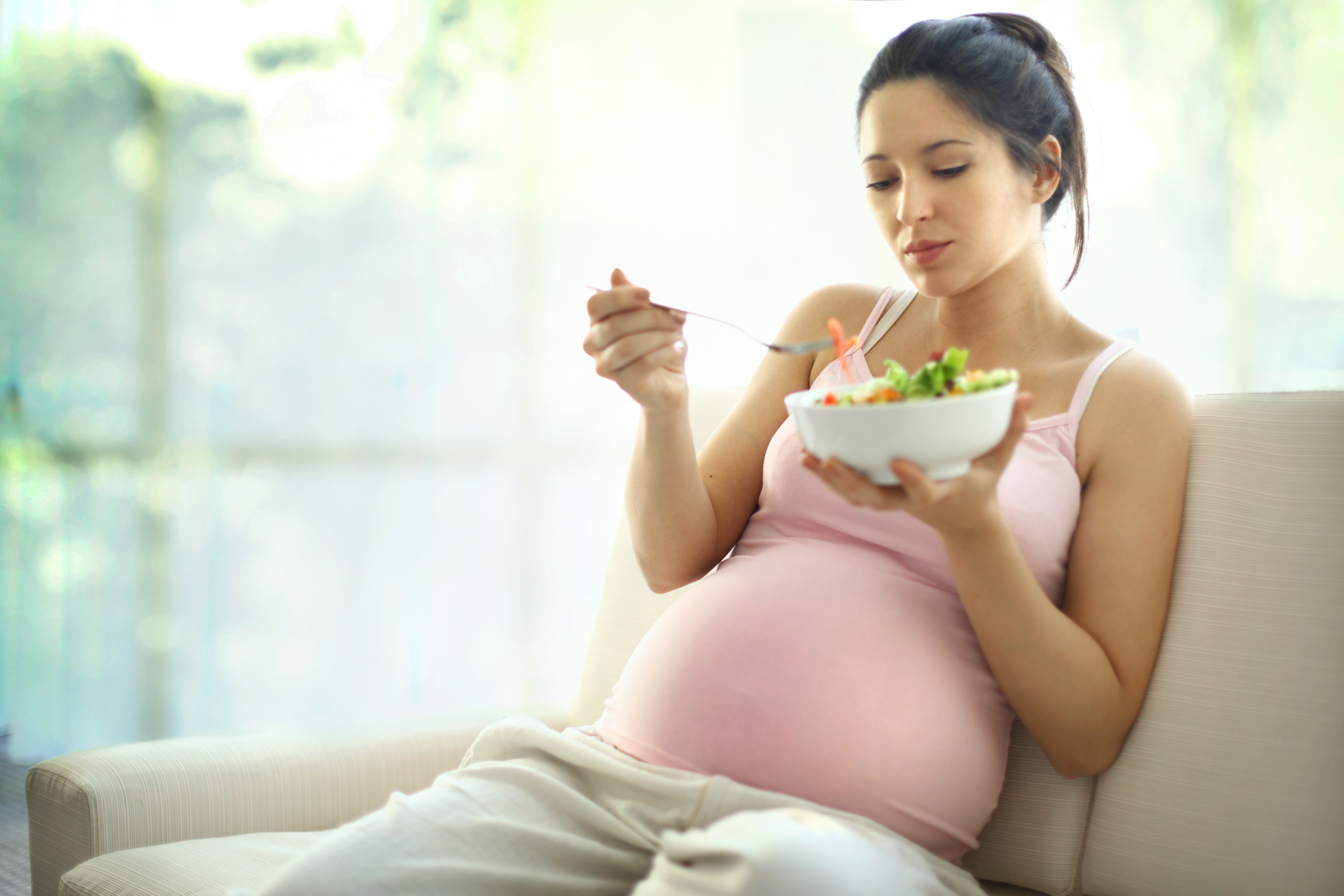 Pregnant woman eating salad.