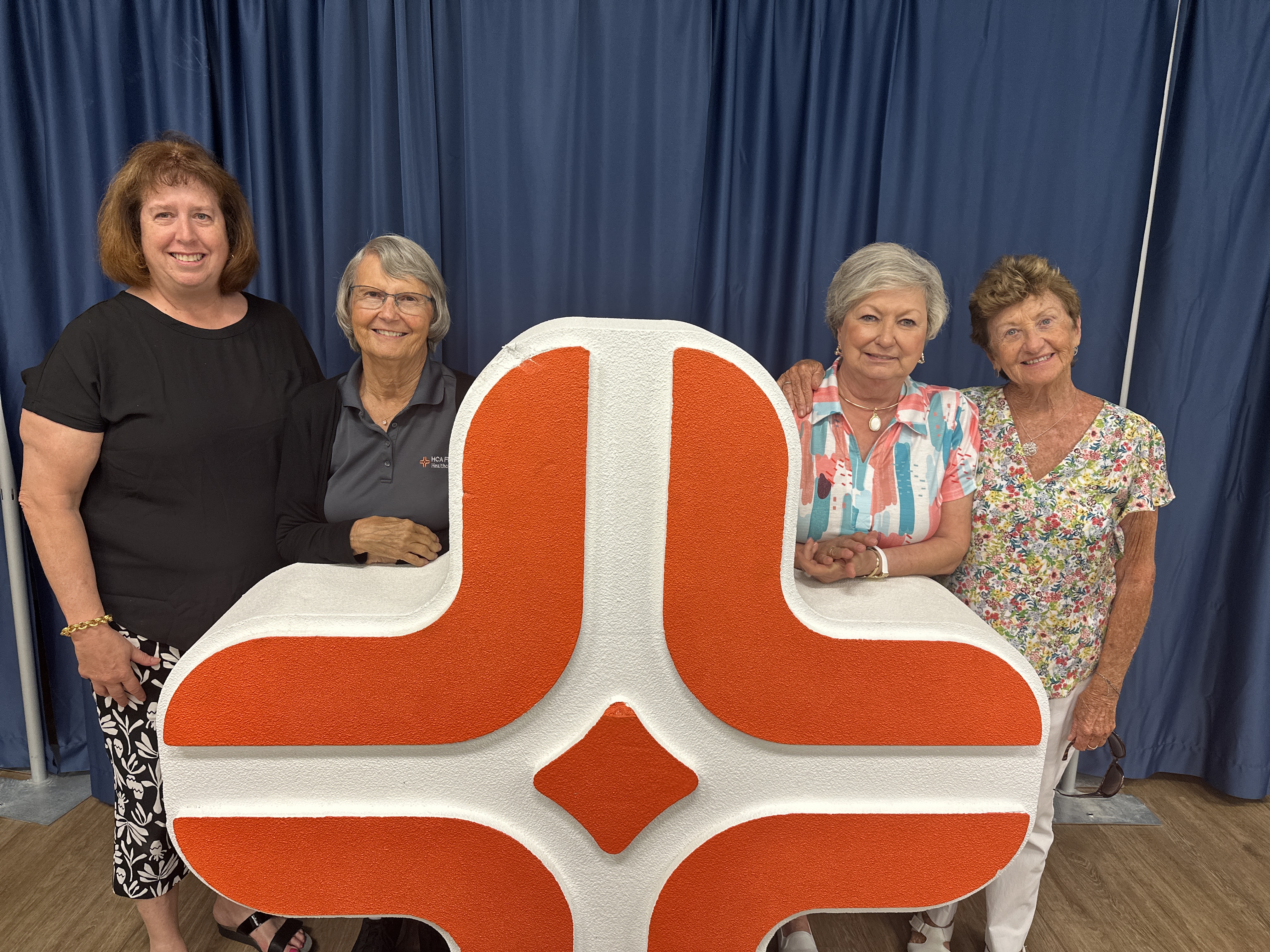 Four women, Dr. Karen Weinstein, Rann Hopp, Barb Artiglier and Grace Drescher pose with the HCA Florida Englewood Hospital logo statue.