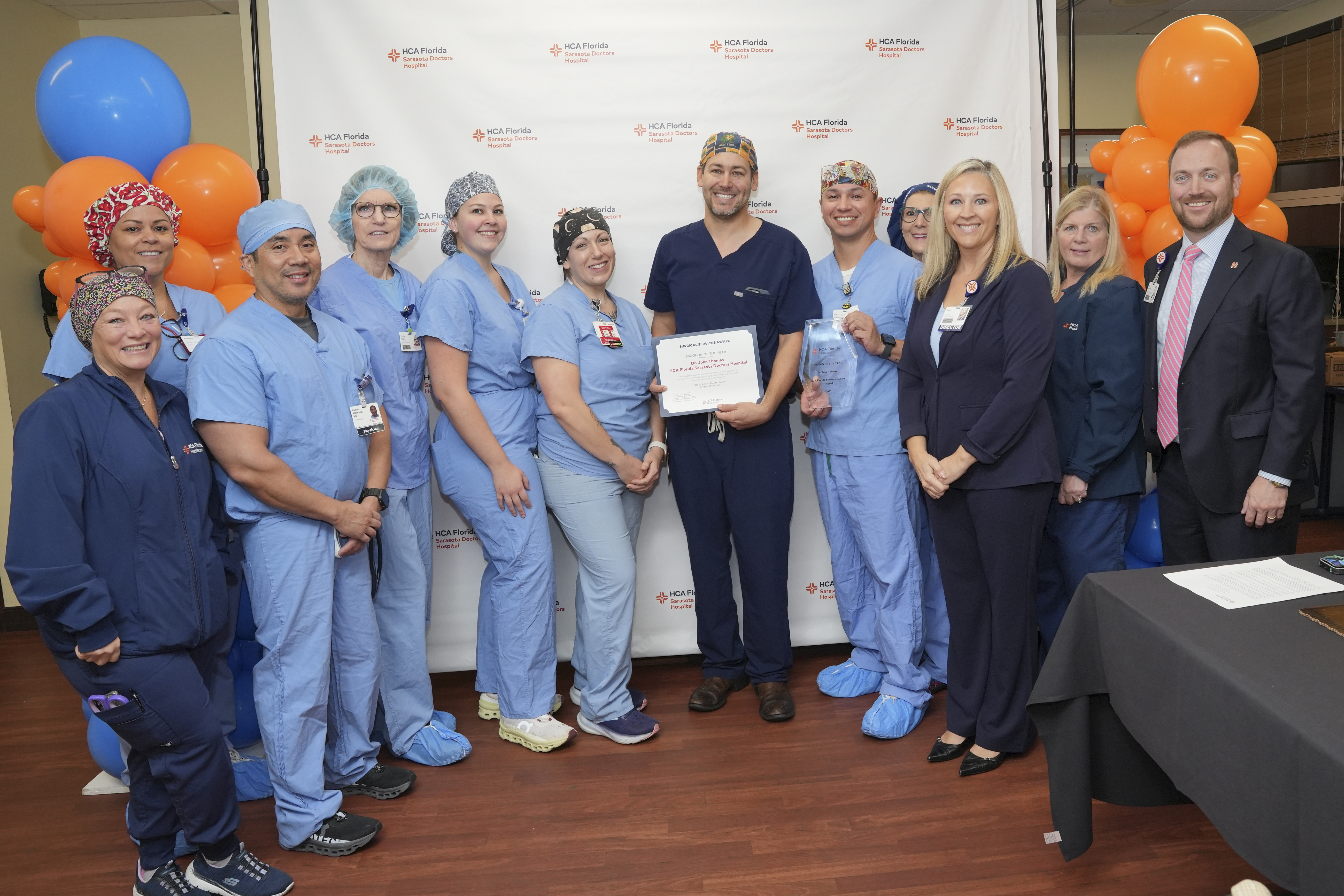 Doctor stands smiling with nurses holding award.