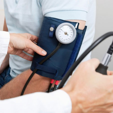A closeup of a person's arm wearing a blood pressure cuff with a medical professional operating the meter.
