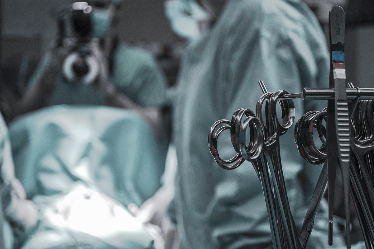 A surgical team performing a procedure in an operating room, with multiple sets of surgical scissors in the foreground.