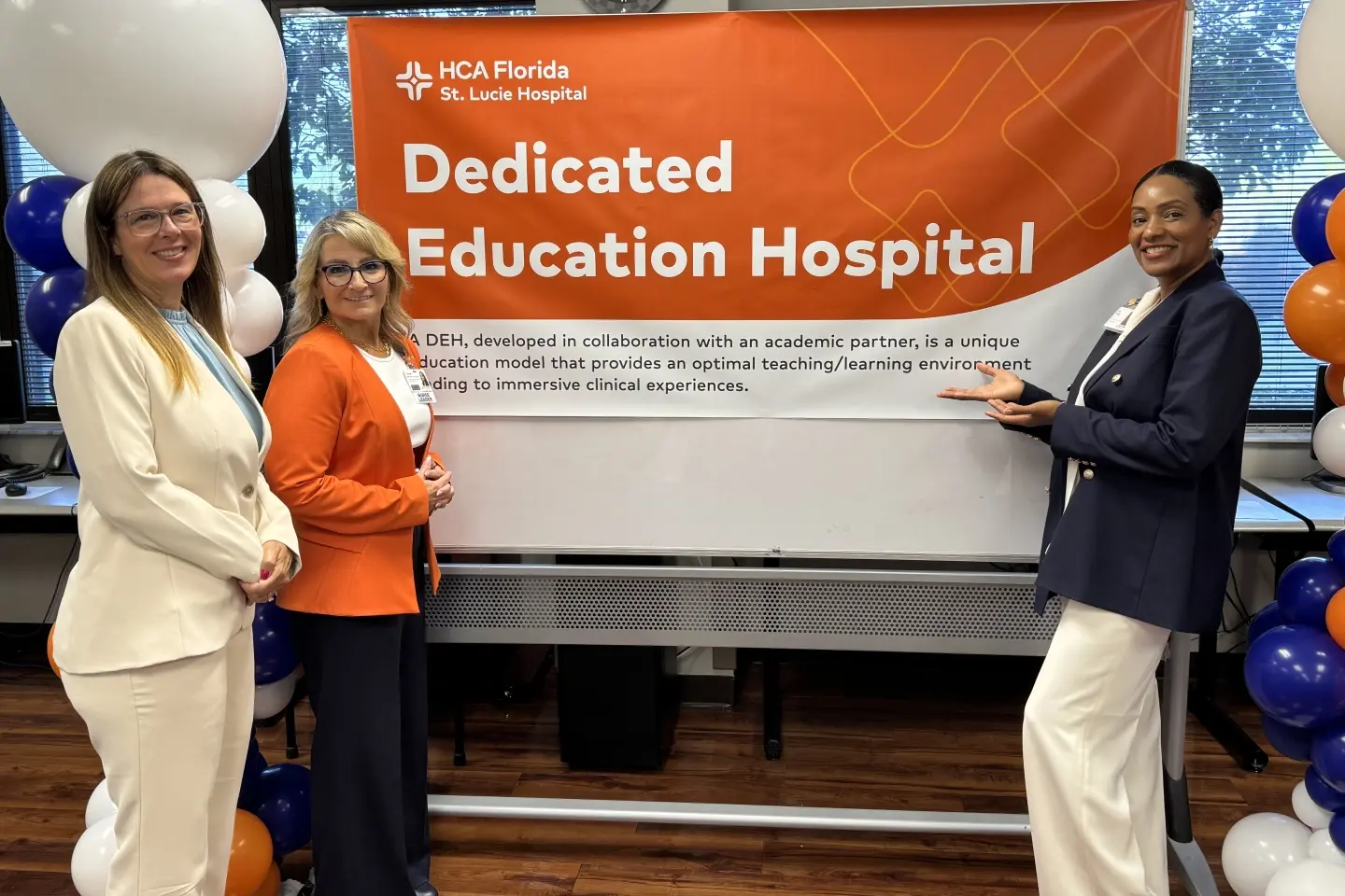 St. Lucie team leaders stand in front of sign reading "Dedicated Education Hospital."