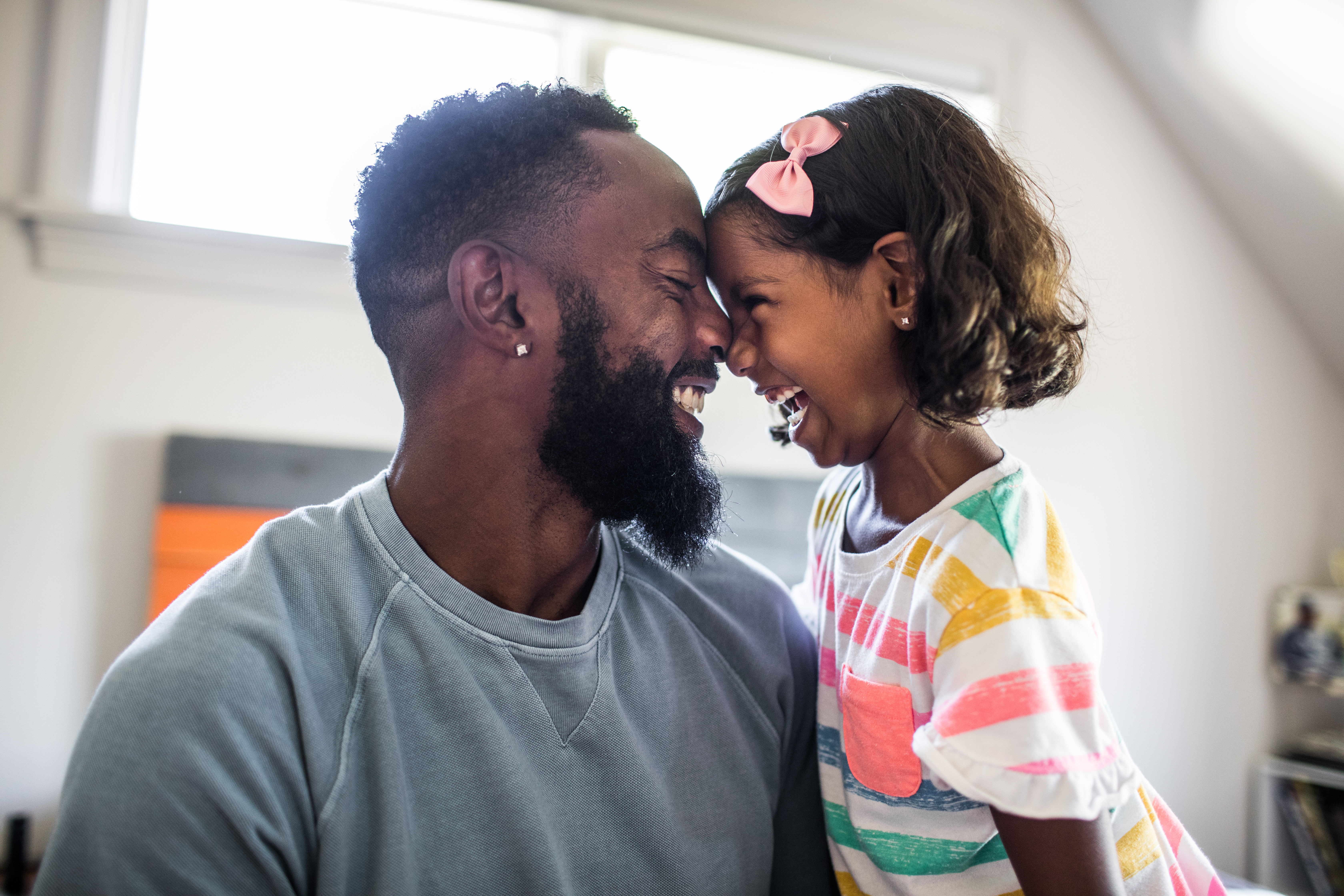 Father and child laughing while their foreheads touch