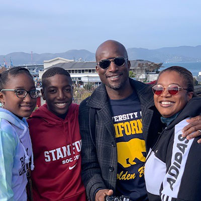 Mahntie Reeves with his wife and two teenage children, pose with a scenic mountain view in the background.