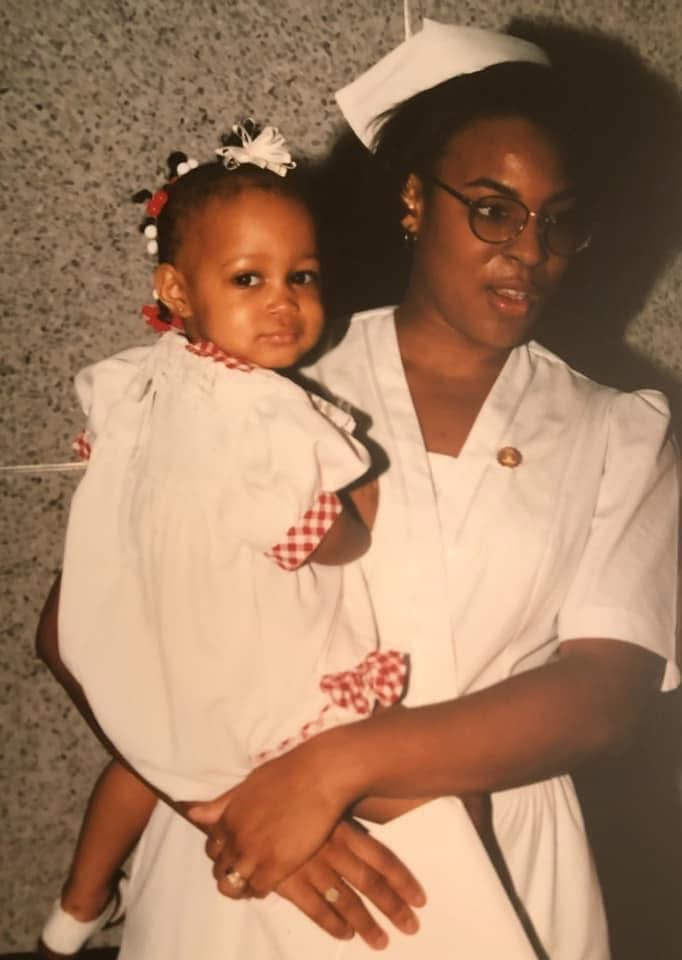 Dana Hubbard holds her young daughter, Arin, in her arms while wearing a nurses' uniform