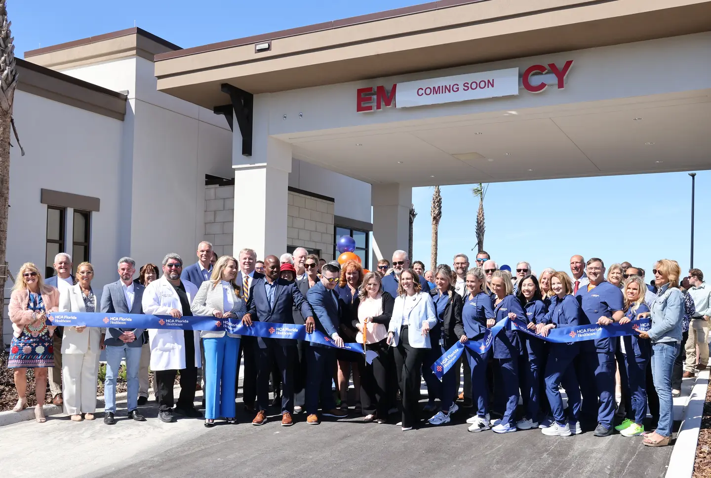 Large group of providers and staff stand in front of Wellen Park Emergency entrance to cut inaugural ribbon.