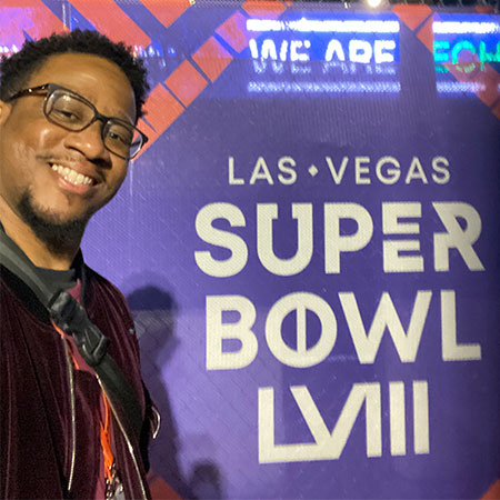 Chris Allen smiling and posing near the Super Bowl Las Vegas sign.