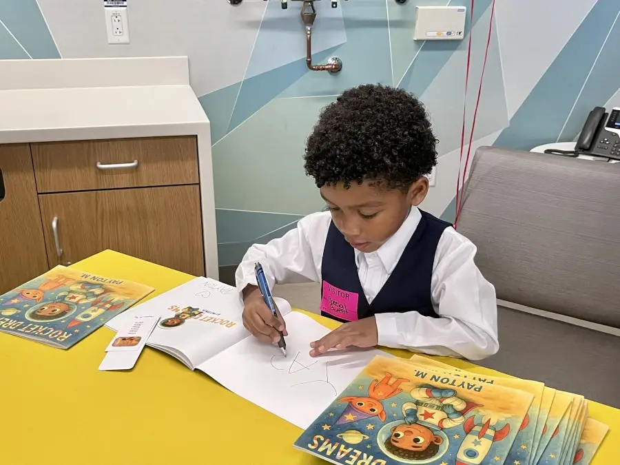 Young boy Payton seated at table with books.